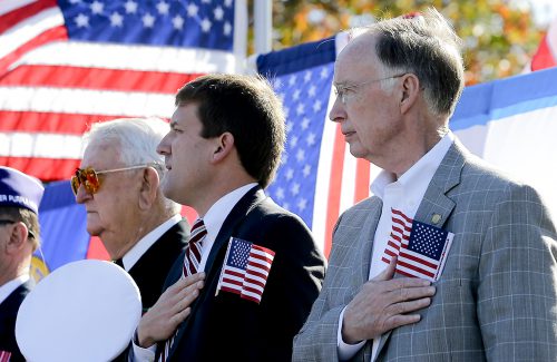 Alabama Governor Robert Bentley, right, and state Rep. Bill Poole, beside Gov. Bentley, and others during the singing of the National Anthem on Veterans Day in Tuscaloosa, Ala., Tuesday, Nov. 11, 2014.